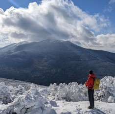 A man stands on top of a mountain in Vermont as an advertisement for Eastern Mountain Sports